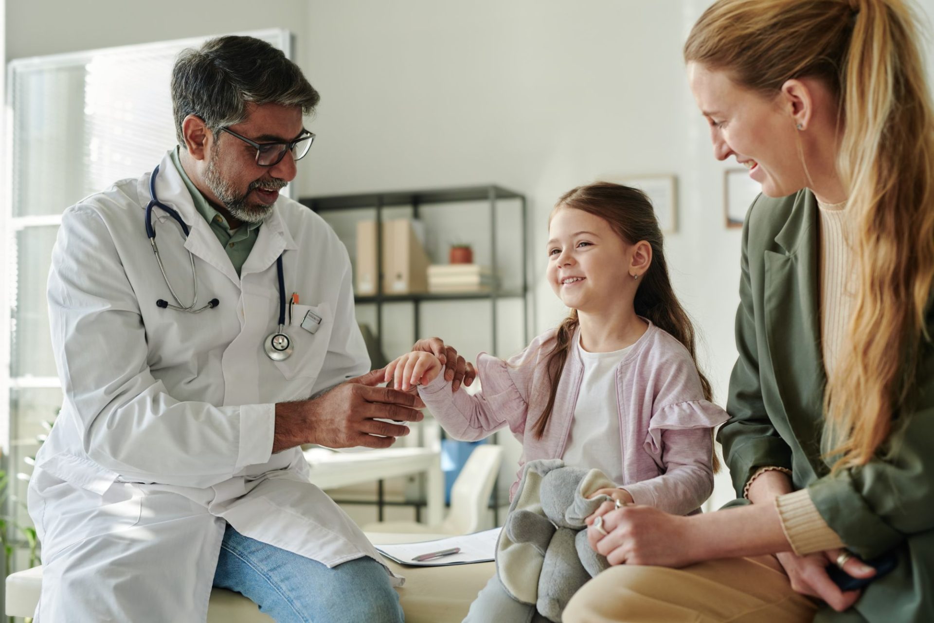 A smiling child visits a doctor with their mother